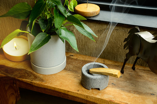 Imagen de una consola con un recipiente Mol y palo santo, una maceta Karla y una vela spin en un espacio para meditar.