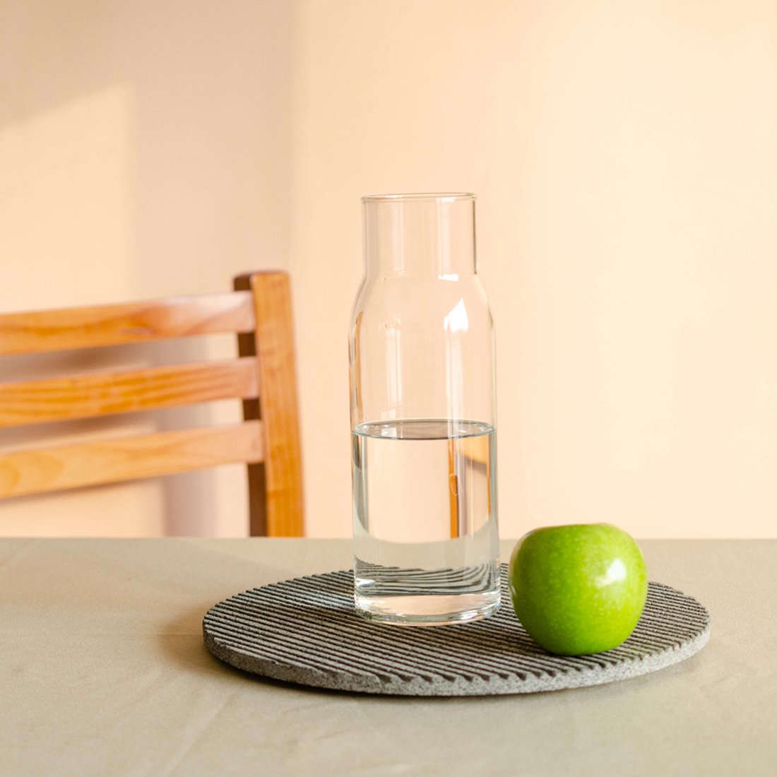 Plato Ig con una jarra de vidrio y manzana con luz de atardecer.